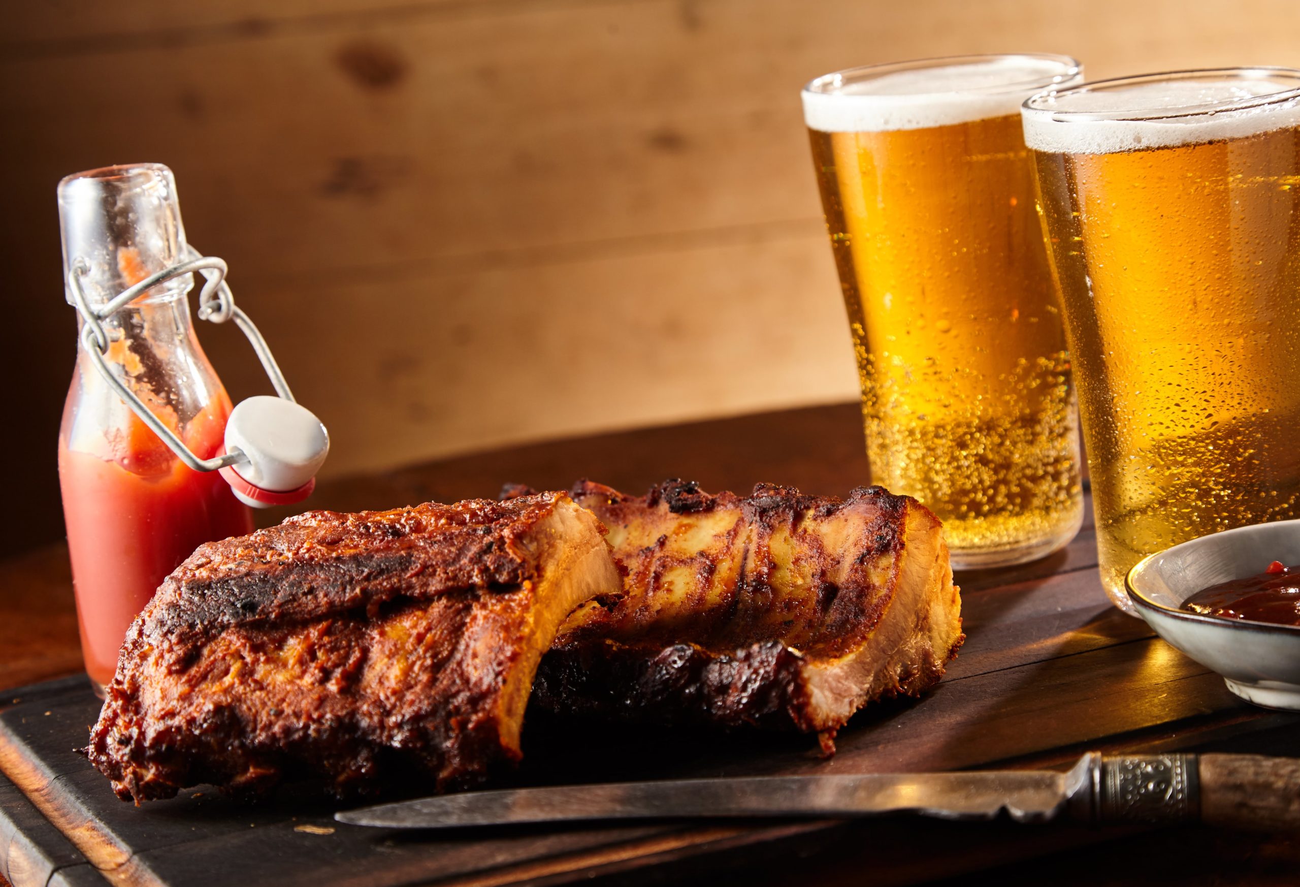 rack of ribs alongside bbq sauce and beer